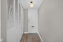 Entryway featuring wood-finish flooring, a white entry door with brass hardware, and a modern globe light fixture - #1804 10883 Saskatchewan Dr Nw, Edmonton, AB  - Indoor Photo Showing Other Room 