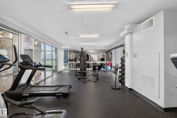 Fitness center featuring extensive full-height windows, durable black rubber flooring, and bright overhead fluorescent lighting - 