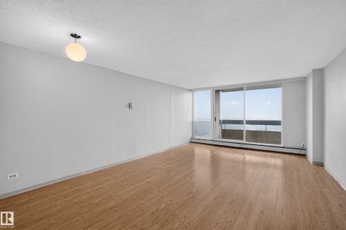 Bright interior space featuring wood-finish flooring and a large sliding glass door - #1508 10883 Saskatchewan Dr Nw Nw, Edmonton, AB - Indoor Photo Showing Other Room