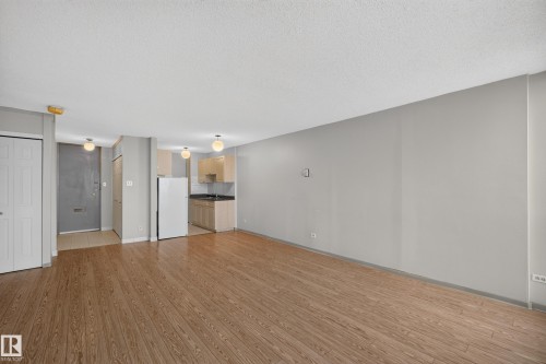 Open-concept living area featuring wood-finish flooring, light grey painted walls, and a visible kitchen area with light wood cabinetry - #1508 10883 Saskatchewan Dr Nw Nw, Edmonton, AB - Indoor