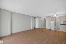 Open-concept living area featuring wood-finish flooring, light gray wall paint, and a textured white ceiling - 