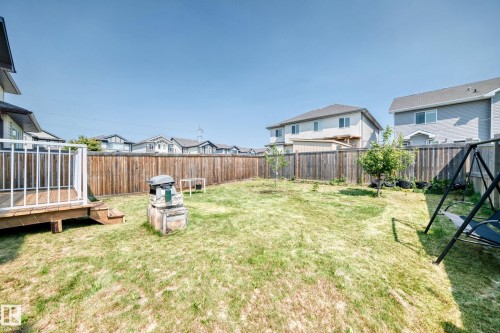 Expansive grassy yard featuring a wood fence perimeter, a wood deck with white railings, and established trees - 2923 16 Street Nw, Edmonton, AB - Outdoor With Deck Patio Veranda With Backyard