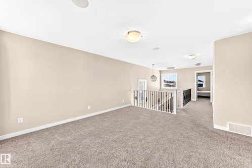 Expansive carpeted loft space featuring neutral walls, recessed ceiling speakers, and multiple flush-mount light fixtures - 2923 16 Street Nw, Edmonton, AB - Indoor Photo Showing Other Room