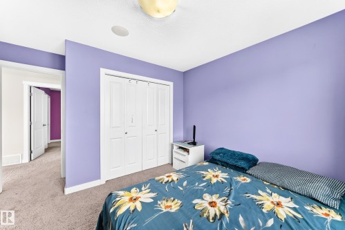 Bedroom featuring a built-in closet with bi-fold doors, white trim, and light-colored carpet flooring - 2923 16 Street Nw, Edmonton, AB - Indoor Photo Showing Bedroom