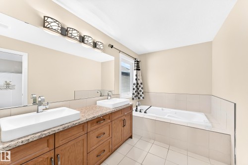 Bathroom featuring a dual vanity with rectangular vessel sinks, a light-toned stone-finish countertop, and wood cabinetry - 2923 16 Street Nw, Edmonton, AB - Indoor Photo Showing Bathroom