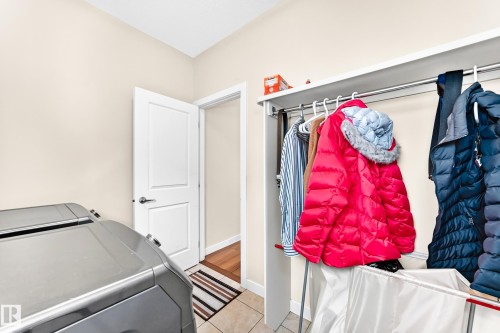 Dedicated laundry area featuring tile flooring, a white interior door with dark hardware, and a built-in closet system with shelving and hanging rods - 2923 16 Street Nw, Edmonton, AB - Indoor Photo Showing Laundry Room