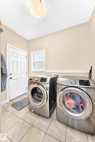 Laundry area featuring light-toned tile flooring, a white paneled door, and a single window with blinds - 2923 16 Street Nw, Edmonton, AB - Indoor Photo Showing Laundry Room