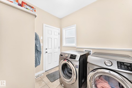 Laundry area featuring tiled flooring, a white paneled door, and a window with horizontal blinds - 2923 16 Street Nw, Edmonton, AB - Indoor Photo Showing Laundry Room