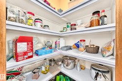 Corner pantry featuring multiple white shelves and light wood-finish trim - 