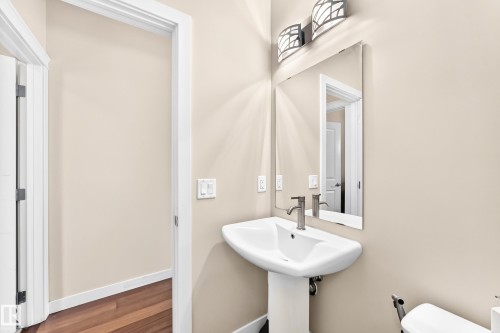 Pedestal sink with a brushed nickel faucet, framed mirror, and decorative wall sconces - 2923 16 Street Nw, Edmonton, AB - Indoor Photo Showing Bathroom