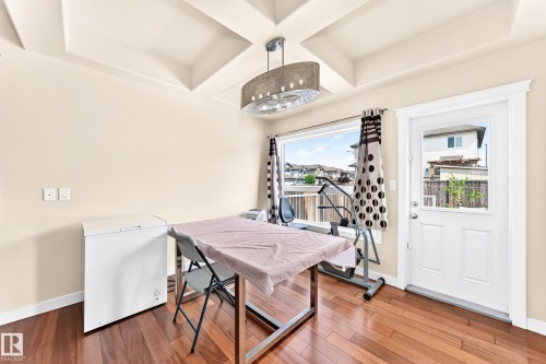 Recessed tray ceiling with a contemporary pendant light fixture, wood-finish flooring, and a glass-paneled exterior door - 2923 16 Street Nw, Edmonton, AB - Indoor
