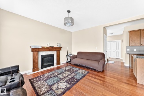 Spacious living room featuring hardwood flooring, a wood-burning fireplace with wood mantel, and recessed ceiling lighting - 2923 16 Street Nw, Edmonton, AB - Indoor Photo Showing Living Room With Fireplace