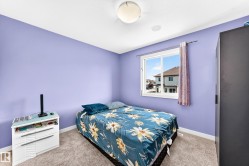 Spacious living area featuring a wood-finish floor, a large window, a fireplace with a wood mantle and tile surround, a vaulted ceiling, and a prominent ceiling fixture - 