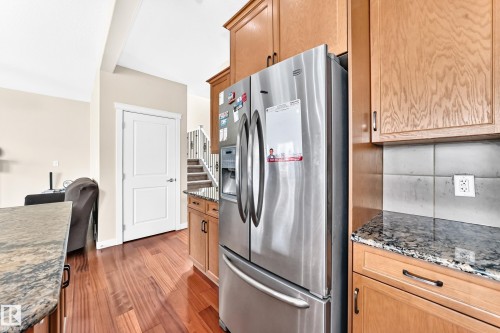 Kitchen area featuring stainless steel appliances, wood-finish flooring, granite countertops, and light wood cabinetry - 2923 16 Street Nw, Edmonton, AB - Indoor Photo Showing Kitchen