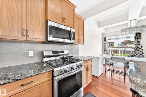 Kitchen featuring wood cabinetry, stainless steel appliances, stone countertops, and tile backsplash - 2923 16 Street Nw, Edmonton, AB - Indoor Photo Showing Kitchen