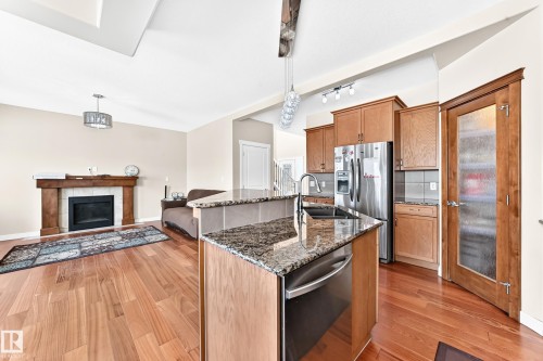 Open-concept kitchen featuring granite countertops, stainless steel appliances, and wood-finish flooring - 2923 16 Street Nw, Edmonton, AB - Indoor Photo Showing Kitchen With Stainless Steel Kitchen With Double Sink With Upgraded Kitchen