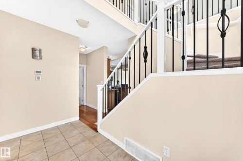 Entryway featuring tile flooring, a two-story ceiling, and a staircase with white railing and black iron balusters - 2923 16 Street Nw, Edmonton, AB - Indoor Photo Showing Other Room