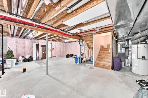 Unfinished basement space featuring a concrete floor, exposed wood joists, utility access, and an unfinished staircase - 2923 16 Street Nw, Edmonton, AB - Indoor Photo Showing Basement