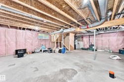 Unfinished basement featuring exposed wood joists, concrete flooring, and insulated walls - 