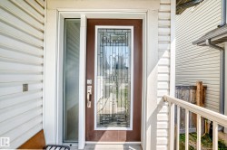 Entry door with decorative leaded glass paneling, full-length sidelight, and an integrated bronze handle set - 