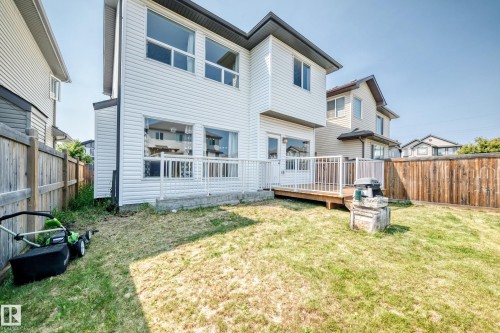 Spacious backyard featuring a level lawn with mature landscaping, wooden privacy fencing, and a multi-level deck with white railings - 2923 16 Street Nw, Edmonton, AB - Outdoor With Deck Patio Veranda With Exterior
