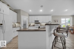 Kitchen featuring white cabinetry, an island with a breakfast bar, recessed lighting, tile flooring, and a sliding glass door - 