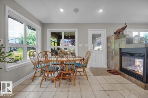 Tile flooring extends through this room, featuring a built-in fireplace with a stone surround - 928 Thompson Place Nw, Edmonton, AB - Indoor Photo Showing Dining Room With Fireplace