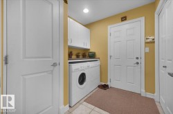 Dedicated laundry area featuring a white front-load washer and dryer, upper cabinetry, and a countertop - 