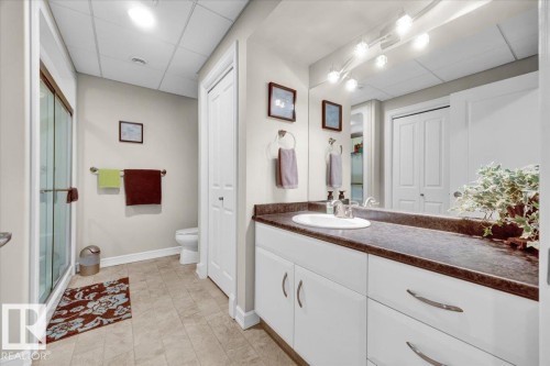 Bathroom vanity featuring a single basin, dark countertop, and white cabinetry with curved hardware - 928 Thompson Place Nw, Edmonton, AB - Indoor Photo Showing Bathroom