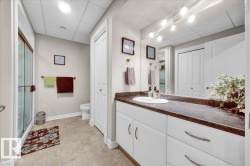 Bathroom vanity featuring a single basin, dark countertop, and white cabinetry with curved hardware - 