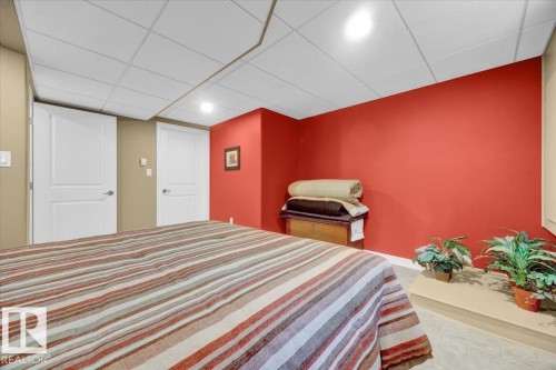 Interior room featuring two panel doors with chrome hardware, an acoustic tile ceiling, recessed lighting, and a neutral-toned flooring - 928 Thompson Place Nw, Edmonton, AB - Indoor Photo Showing Bedroom