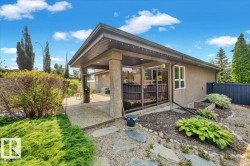 Expansive concrete patio beneath a covered pergola with a stucco exterior - 