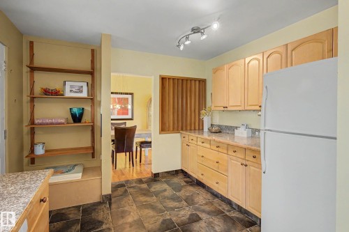 Kitchen featuring light wood cabinetry, stone countertops, and dark tile flooring - 9516 129A Avenue Nw, Edmonton, AB - Indoor Photo Showing Kitchen