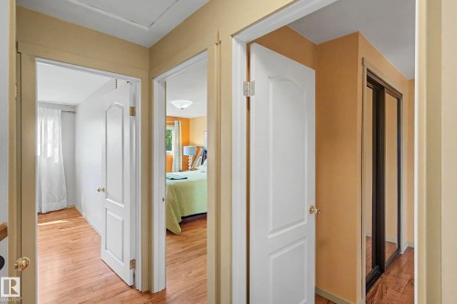 Interior hallway featuring wood-finish flooring, white paneled doors with brass hardware, and light-toned wall paint - 9516 129A Avenue Nw, Edmonton, AB - Indoor Photo Showing Other Room