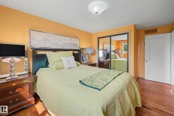 Hardwood flooring extends throughout this room, featuring a white paneled door and mirrored closet doors - 