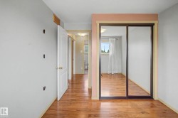 Hardwood-finish flooring throughout, featuring a mirrored sliding closet door, white trim, and a white interior door - 