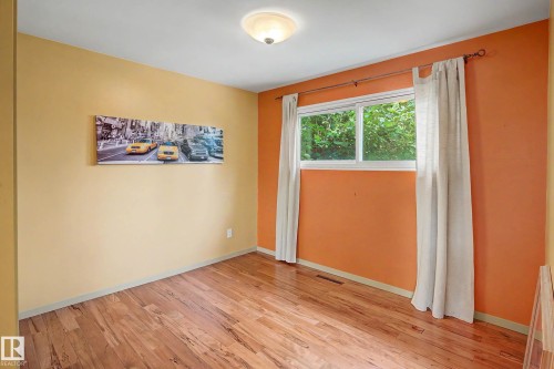 Room featuring wood-finish flooring, a contemporary ceiling light fixture, and a large window - 9516 129A Avenue Nw, Edmonton, AB - Indoor Photo Showing Other Room