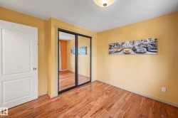 Room featuring wood-finish flooring, a white paneled door, and mirrored closet doors with dark frames - 