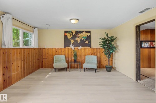 Spacious room featuring light wood-finish flooring, natural wood paneling, and a contemporary ceiling light fixture - 9516 129A Avenue Nw, Edmonton, AB - Indoor Photo Showing Other Room