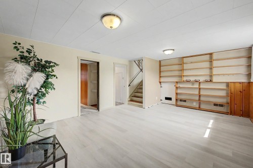 Spacious room featuring light wood-finish flooring, built-in shelving, white paneled ceilings, and neutral wall tones - 9516 129A Avenue Nw, Edmonton, AB - Indoor