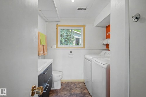Bathroom featuring a vanity with dark cabinetry and chrome hardware, a toilet, and a window with wood trim - 9516 129A Avenue Nw, Edmonton, AB - Indoor