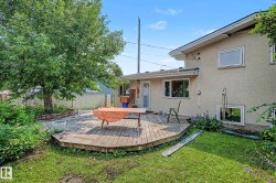 Expansive backyard featuring a multi-level wooden deck, mature tree, and perimeter fencing - 