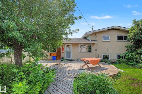 Spacious backyard featuring a multi-level deck, mature trees, and a stucco exterior - 9516 129A Avenue Nw, Edmonton, AB - Outdoor