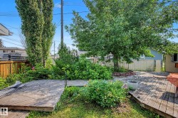 Expansive backyard featuring a multi-level wood deck, mature trees, and established perimeter landscaping - 