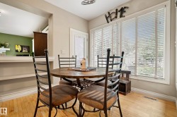 Dining area featuring wood-finish flooring, a large window with horizontal blinds, and a white trim package - 