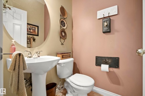 Pedestal sink with chrome fixtures and an oval mirror, complemented by beige and rose-toned wall finishes - 416 Sparling Crest Sw, Edmonton, AB - Indoor Photo Showing Bathroom