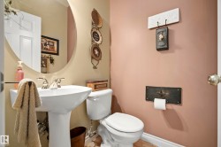 Pedestal sink with chrome fixtures and an oval mirror, complemented by beige and rose-toned wall finishes - 