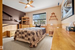Carpeted room featuring a ceiling fan with integrated lighting, wood-finish wainscoting, a window with horizontal blinds, and a built-in wall shelf - 