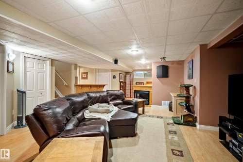 Finished basement offering wood-finish flooring, a built-in bar, recessed lighting, and an integrated fireplace with a mantel - 416 Sparling Crest Sw, Edmonton, AB - Indoor With Fireplace