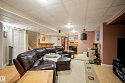 Finished basement offering wood-finish flooring, a built-in bar, recessed lighting, and an integrated fireplace with a mantel - 
